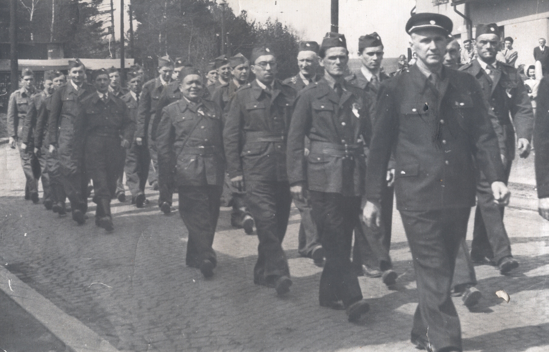 Jedni z prvních rychnovských hasičů po roce 1945  (vpředu velitel pan Chvalina, v první dvojici za ním zleva pan J. Pivrnec a A. Mareš, v druhé řadě pan J. Erben a dále pan Coufal – trubač hasičů, pan Vodháněl. V pozadí můžeme poznat pana A. Melouna, Š. Melouna, pana Linku a další.)